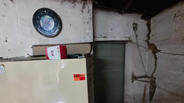 Casa con una refrigeradora y una pared agrietada. 