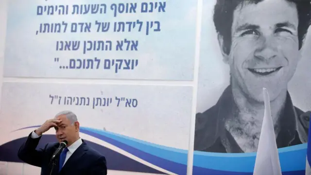 Benjamin Netanyahu discursa diante de um cartaz com a imagem de seu falecido irmão, Yonatan, durante cerimônia em homenagem a ele