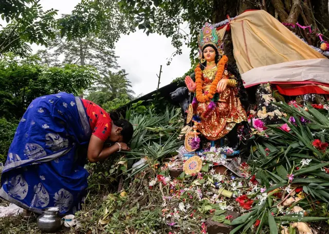 Une femme s'inclinant devant une poupée en signe d'adoration