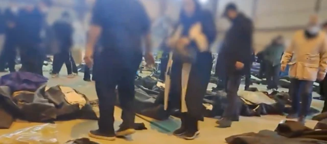 Un grupo de personas busca entre los cuerpos en la morgue de Kahrizak para identificar a sus seres queridos.