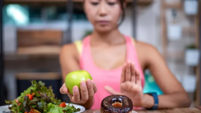 Perempuan menolak makan donat dan memilih apel dan sayuran