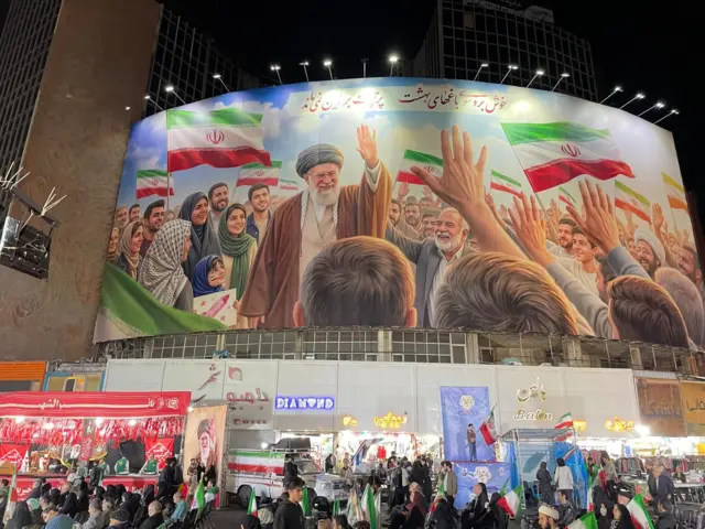 Um grande mural retratando o falecido aiatolá Ali Khamenei está pendurado em uma movimentada rua comercial.