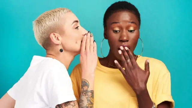 Una mujer le cuenta un secreto a otra.