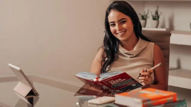 Advogada Luiza Wanderley segurando livro e caneta enquanto sorri