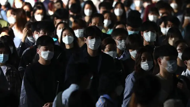 Pessoas andando pela rua usando máscaras