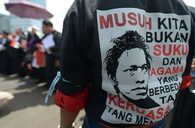 Seorang demonstran mengenakan kaos bertuliskan, "Musuh kita bukanlah keberagaman agama atau ras, tetapi pemerintah yang menindas".
