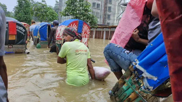 কোমরসমান পানিতে রিকশা টেনে নিয়ে যাচ্ছেন এক রিকশাচালক। 