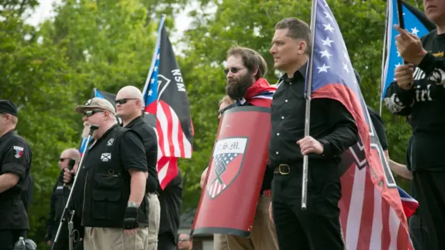 Homens seguram bandeiras dos EUA durante manifestação nazista