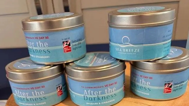 Tony's range of candles assembled on top of each other. They have light blue containers and have VE Day logos on them.