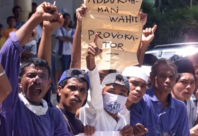 Para pengunjuk rasa Muslim mengacungkan kepalan tangan di depan spanduk yang mengecam "para provokator" pada 12 Maret 1999, saat aksi unjuk rasa di luar Masjid Al-Fatah, Ambon, setelah salat Jumat.