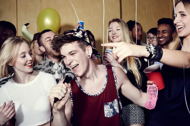 Grupa przyjaciół bawi się i śpiewa na imprezie