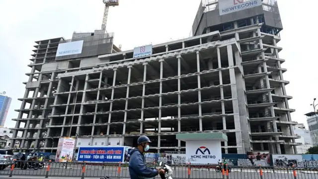 A man riding past a building under construction and owned by the Van Thinh Phat group in Ho Chi Minh City