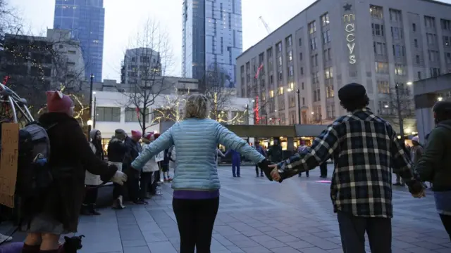 Women dey hold hands, form circle for street.