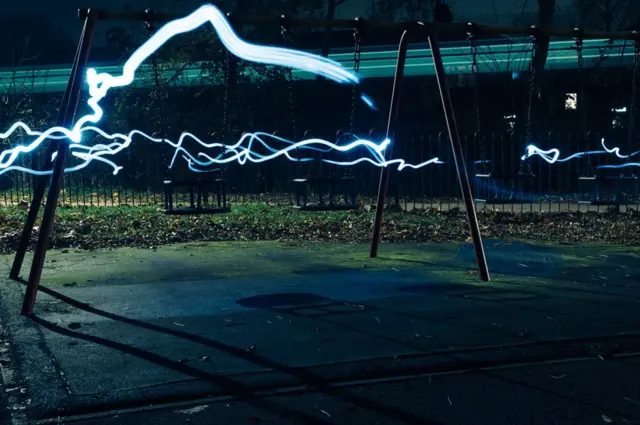 Streams of white light run through an empty playground