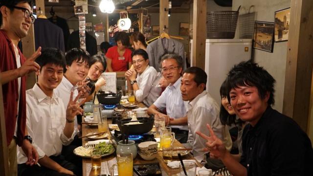 Hombres sentados en un restaurante comiendo y bebiendo tras un día laboral en Japón.