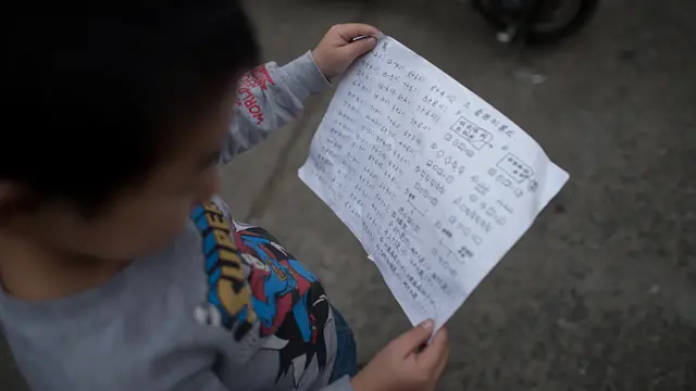 Niño mirando papel con sumas