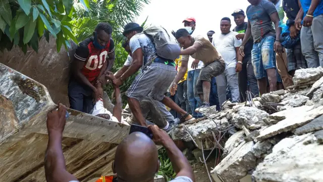 Homens tentam resgatar um sobrevivente debaixoapp de cassino dinheiro realdestroços