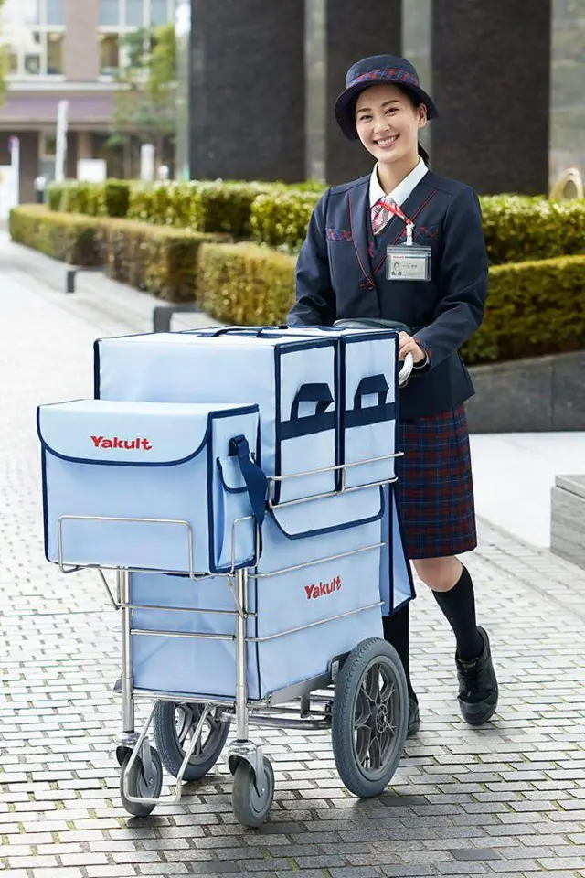 Moça do Yakult empurra carrinho usado para fazer as entregas do produto