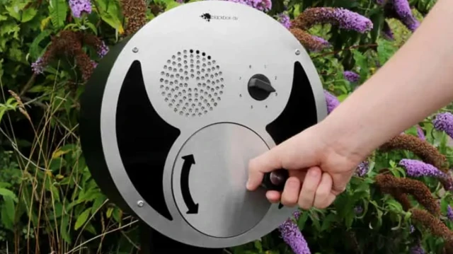 Primer plano del U-Turn Round. Es una caja circular con un frente plateado. Tiene un dial lateral que se puede girar para ajustar el archivo de sonido que se desea reproducir en el altavoz. Hay una mano que gira la manija que genera el sonido.