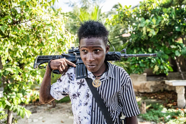 Un joven pandillero de 14 años con un ak47 al hombro y un medallón dorado colgando patrulla las calles del barrio Mariani de Puerto Príncipe, Haití, el 6 de octubre de 2025. Mariani está cerca de la Route Nationale 2, partes de la cual han sido tomadas por pandillas.