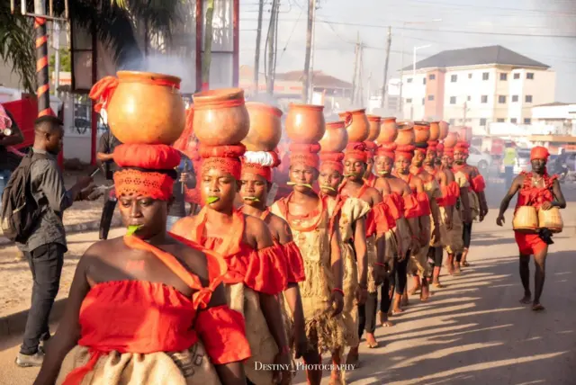 Women dey carry clay pots for head