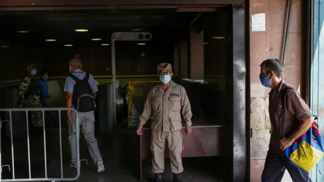 Un miembro de la policía venezolana en una estación del metro de Caracas asegurándose de que ningún pasajero ingrese sin mascarilla.