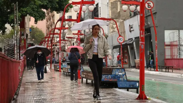 Pessoas caminhasndo na chuva no bairro da Liberdade, no centro de São Paulo