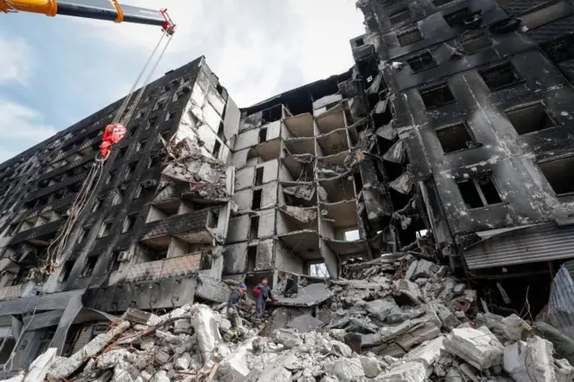 Emergency workers remove debris of a building destroyed in the course of the Ukraine-Russia conflict, in the southern port city of Mariupol, Ukraine April 10, 2022