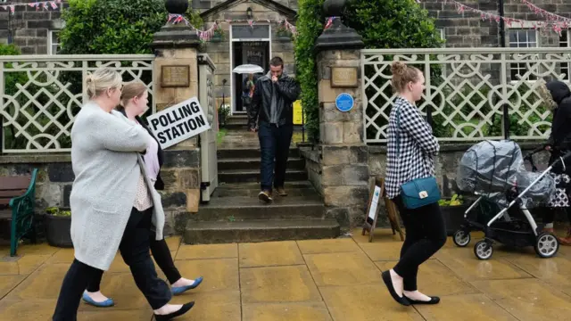 Personas caminan frente a un centro de votación en Reino Unido.