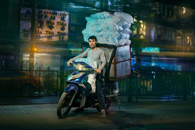 موٹر سائیکل سے منسلک ایک بڑے باکس میں ایک شخص برف کے تھیلے اٹھائے جا رہا ہے