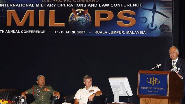 Ông Raul Pedrozo (ngồi giữa) trong sự kiện An ninh hàng hải quốc tế tại Malaysia 2007 với tư cách là Cố vấn luật của Bộ Tư lệnh Thái Bình Dương Mỹ. Bên phải ông là Tham mưu trưởng quân đội Malaysia Abdul Aziz Zainal, bên trái ông Phó Thủ tướng Malaysia Najib Razak đang phát biểu.