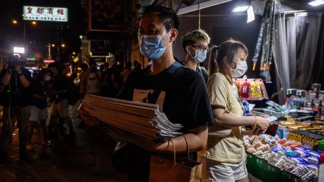 香港九龍旺角街頭一位男子捧著一疊剛買來的《蘋果日報》離開（18/6/2021）