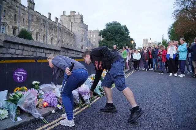 Personas colocan flores frente al castillo de Windsor