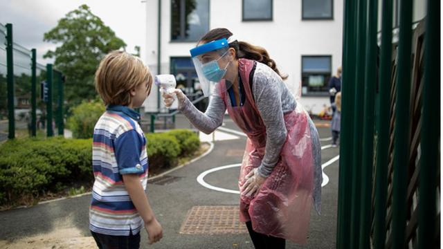 У ребенка измеряют температуру на входе в школу в Лондоне