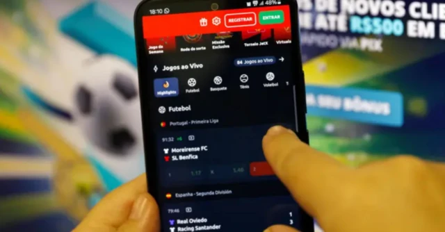 Imagem mostra um telefone celular na mão de alguém com a tela de uma plataforma de jogos online aberta