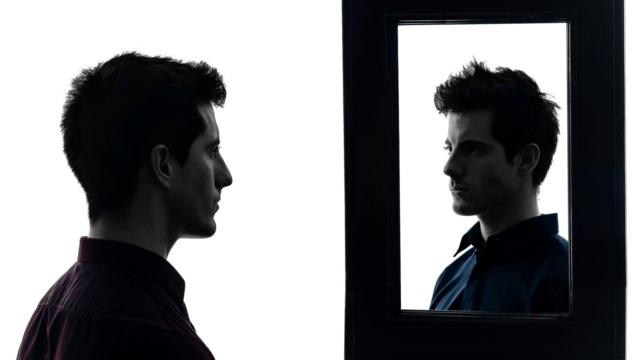 Homem se observando no espelho