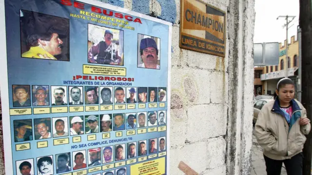 Mujer camina frente a un afiche con las fotos de los miembros del Cartel de Sinaloa, 2005