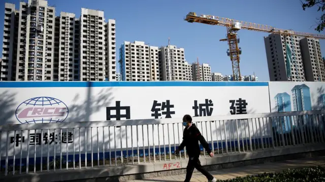 A man wearing a mask walks past a construction site of a residential compound in Beijing, China October 19, 2020.