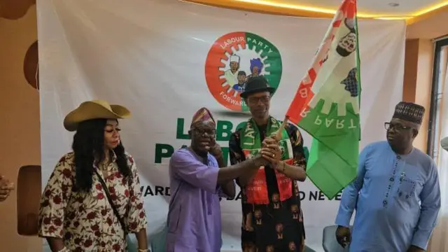 Two men holding flag wit one woman by di side
