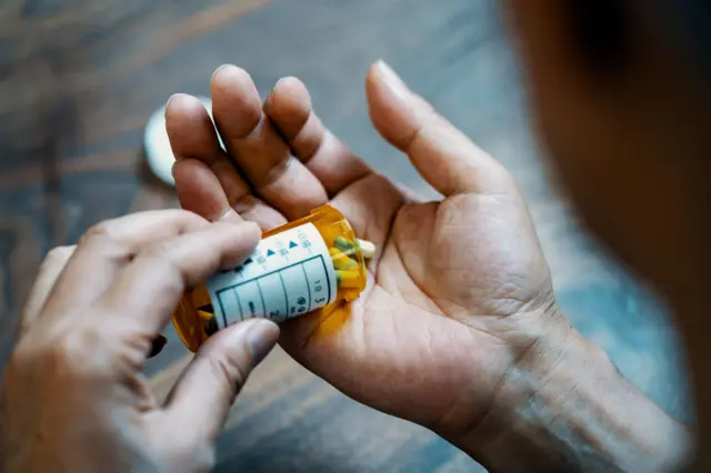 Un hombre sostiene pastillas en su mano