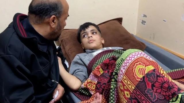 Ibrahim deitado na cama do hospital acompanhado do pai