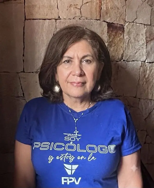 Clara Astorga, de cabello marrón, ve a la cámara. Lleva una camisa azul que dice: "Soy psicólogo y estoy en la FPV".
