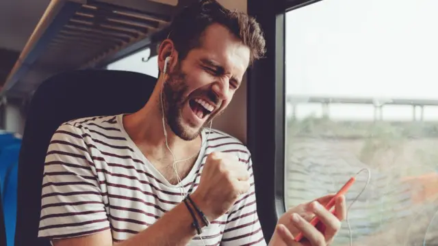 Hombre joven escuchando sonidos con su celular.