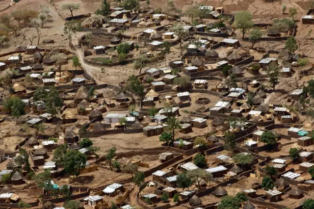 صورةٌ التُقطت من طائرة هليكوبتر في 19 يونيو/حزيران عام 2017 ، تظهرمدينة قولو في منطقة جبل مَرَّة الجبلية ذات الغابات الكثيفة بوسط دارفور، وتظهر في اصورة منازل على شكل أكواخ محاكة بأشجار تعلو منطقة جبلية.