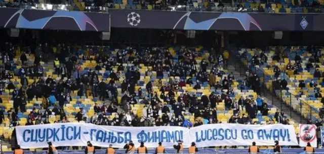 Вболівальники тримають плакат, де написано "Ганьба Динамо", "ЛУческу йди геть"