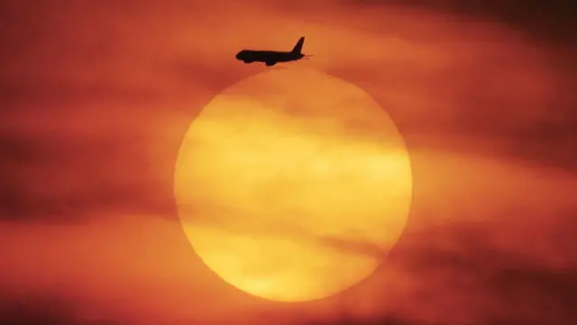 Самолет взлетает из аэропорта Джакарты на фоне закатного солнца