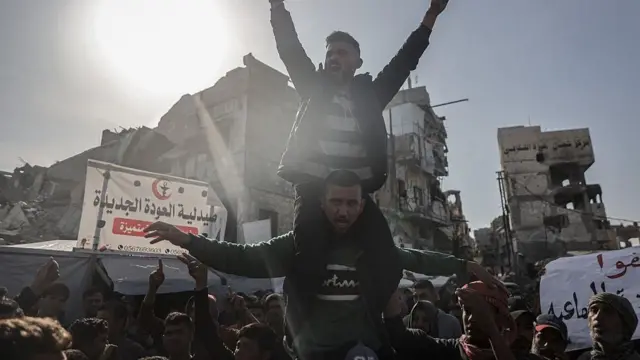 Протестующие палестинцы на фоне разрушенных домов в Бейт-Лахия.