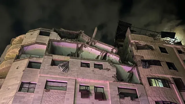攻撃を受けた建物を地上から見上げるように写した写真。上の3階分が破壊され、天井が崩落し、壁がはがれている