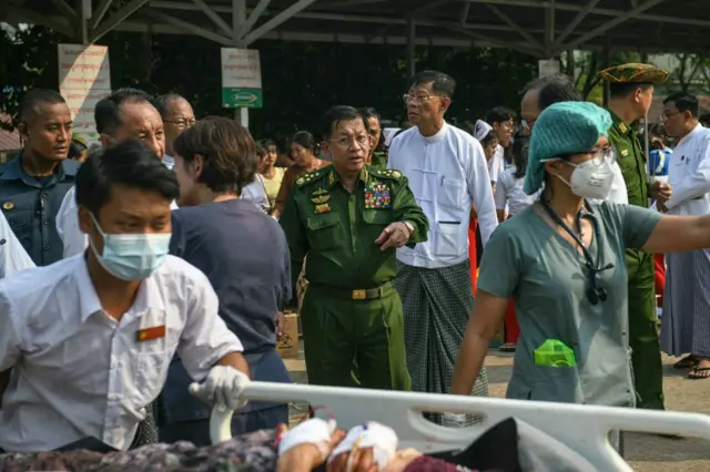 Myanmar's military chief Min Aung Hlaing (C) gestures as earthquake survivors gather in the compound of a hospital in Nay Pyi Taw on March 28, 2025, after an earthquake in central Myanmar.
