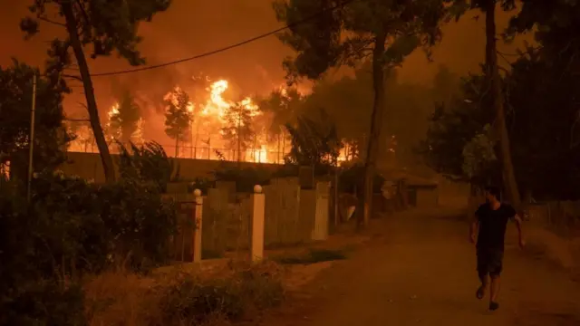 Un hombre se aleja de un incendio en la isla griega de Evia.